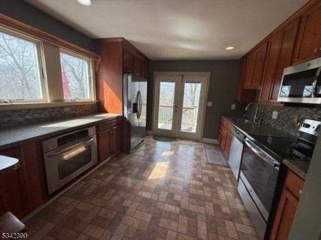 kitchen featuring stainless steel appliances, french doors, a sink, and tasteful backsplash