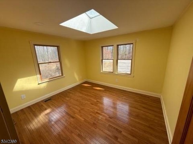 spare room featuring a healthy amount of sunlight, baseboards, and wood finished floors