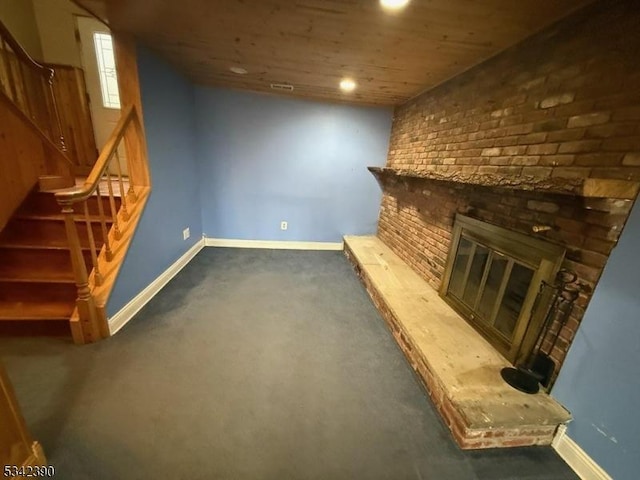 basement featuring a brick fireplace, baseboards, and stairs