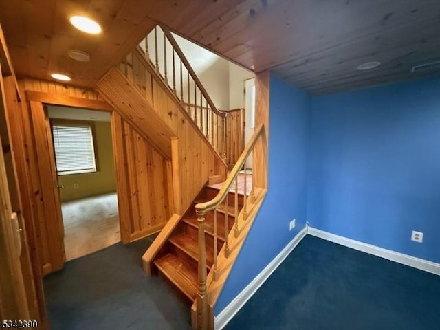 stairway featuring wooden ceiling, carpet, and baseboards