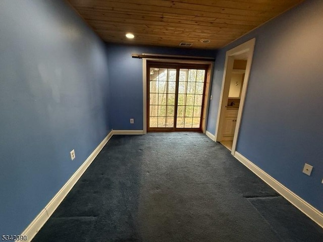 empty room featuring wood ceiling, visible vents, dark carpet, and baseboards