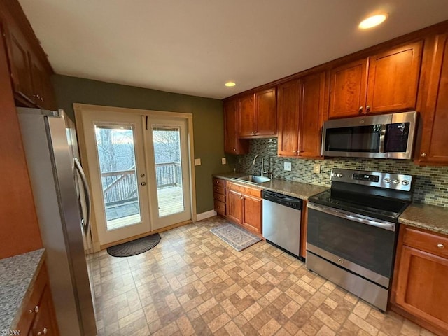 kitchen with french doors, tasteful backsplash, appliances with stainless steel finishes, brown cabinetry, and a sink