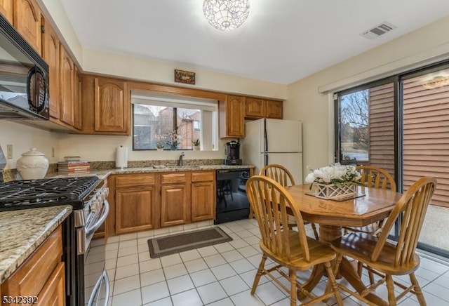 kitchen featuring black appliances, a wealth of natural light, and brown cabinets