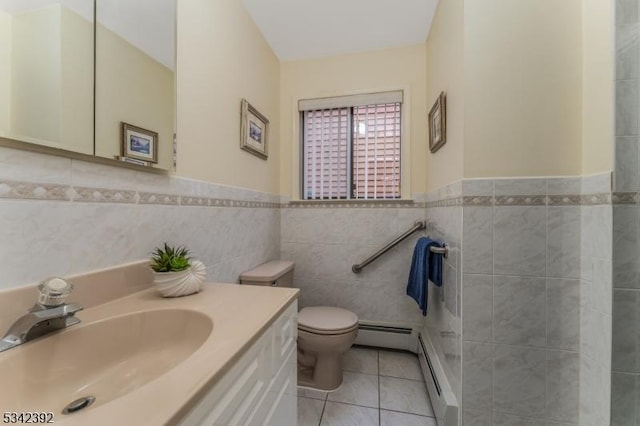 bathroom featuring toilet, a baseboard heating unit, tile walls, vanity, and tile patterned floors