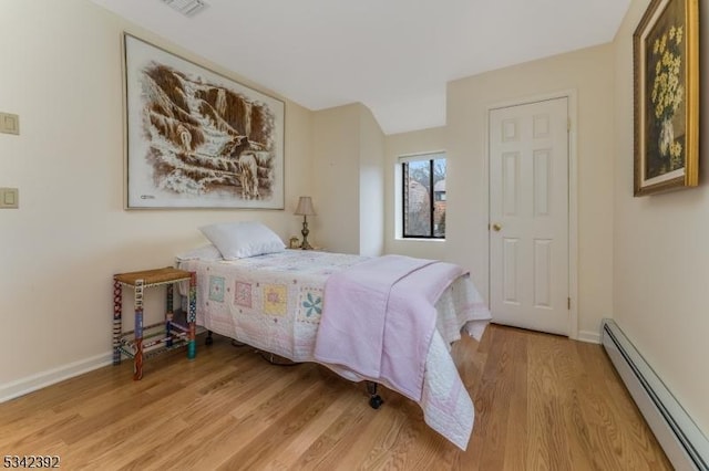 bedroom featuring a baseboard radiator, baseboards, and wood finished floors