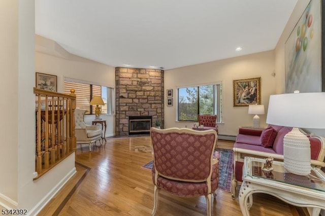 living room with a fireplace, baseboards, baseboard heating, and wood finished floors