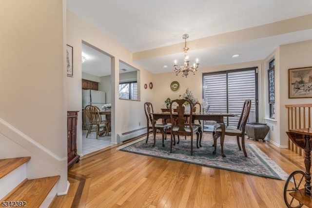 dining room with baseboards, a baseboard radiator, wood finished floors, and a notable chandelier