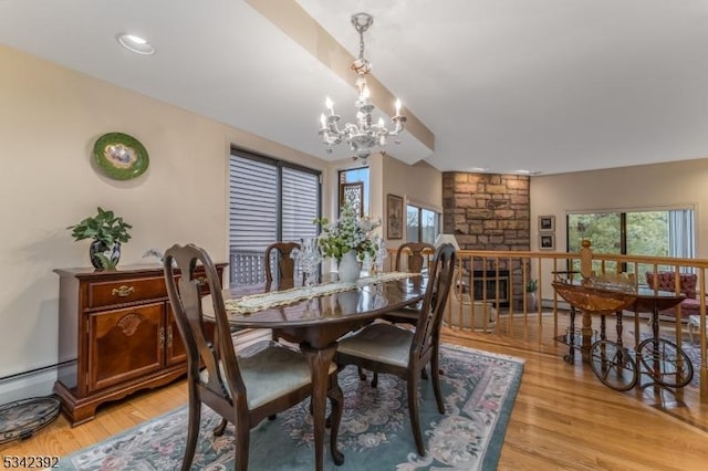 dining space with light wood-type flooring, a healthy amount of sunlight, and a chandelier