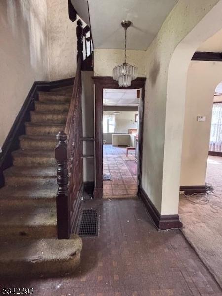 1 Reid Ave, Passaic City, NJ 07055 - entrance foyer featuring an inviting chandelier, visible vents, baseboards, stairway, and arched walkways