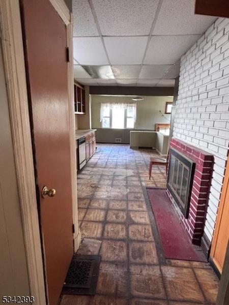 1 Reid Ave, Passaic City, NJ 07055 - unfurnished living room with a brick fireplace, a drop ceiling, and brick floor