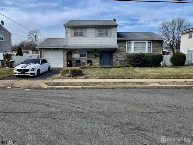 tri-level home with an attached garage, driveway, stone siding, and a front yard