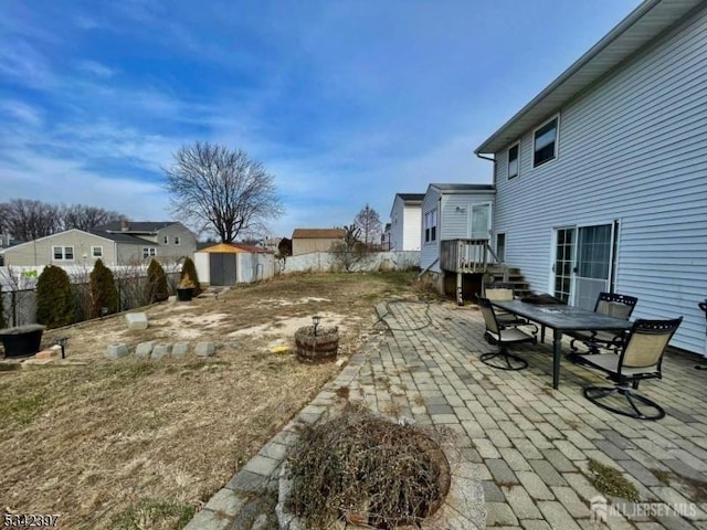 view of yard featuring an outbuilding, a patio, a storage shed, outdoor dining space, and fence