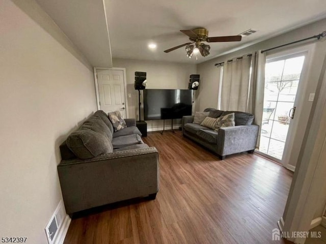 living room with wood finished floors, visible vents, and a ceiling fan