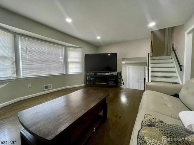 living area featuring lofted ceiling, recessed lighting, visible vents, wood finished floors, and stairs