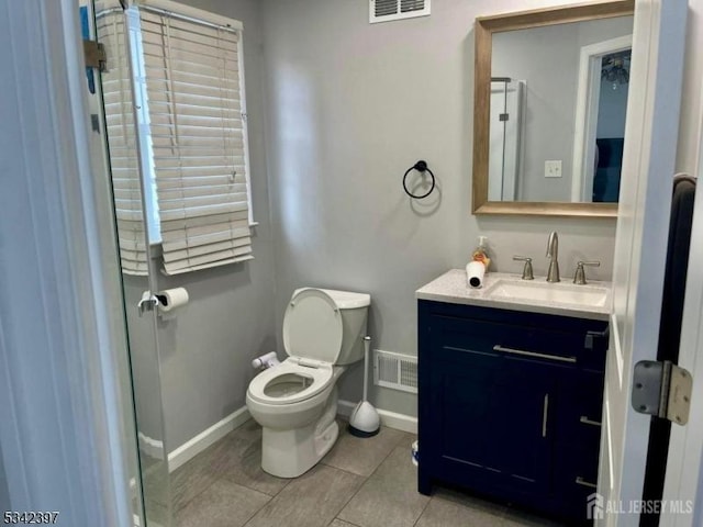 bathroom with toilet, vanity, visible vents, and baseboards