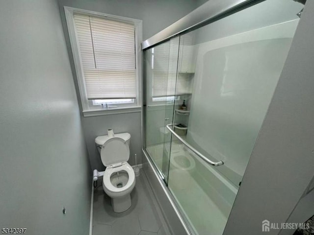 full bath with toilet, bath / shower combo with glass door, and tile patterned floors