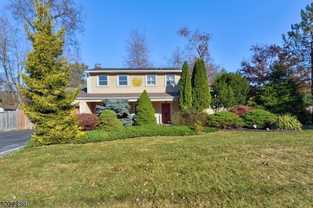 traditional-style home with a front yard, fence, and stucco siding