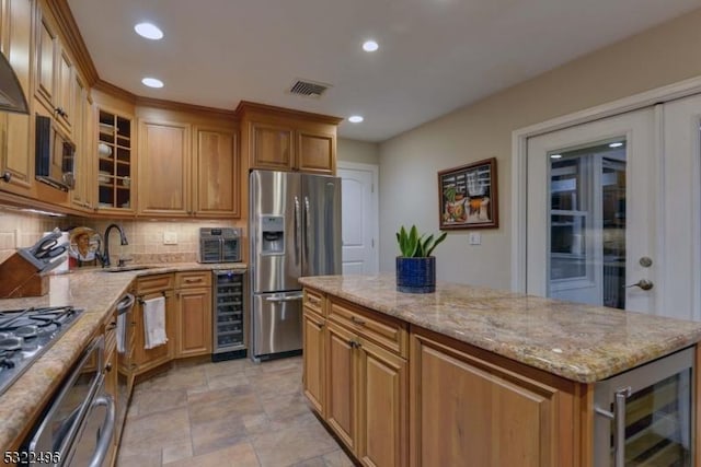 kitchen with appliances with stainless steel finishes, beverage cooler, visible vents, and a sink