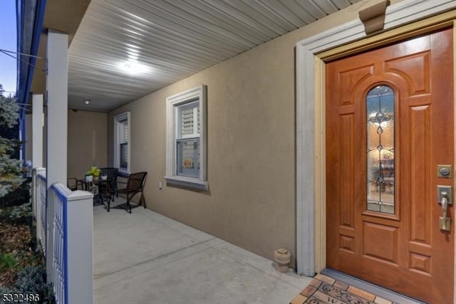 entrance to property with covered porch and stucco siding