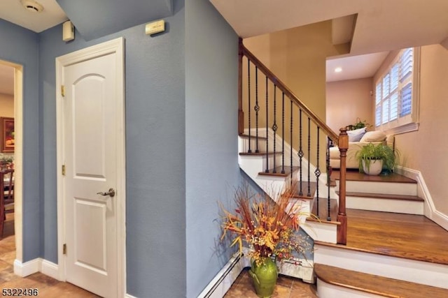 staircase with a baseboard heating unit, a baseboard radiator, and baseboards