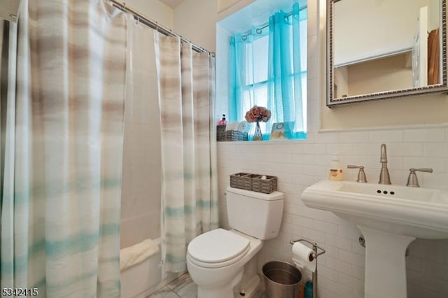 full bathroom with toilet and tile walls