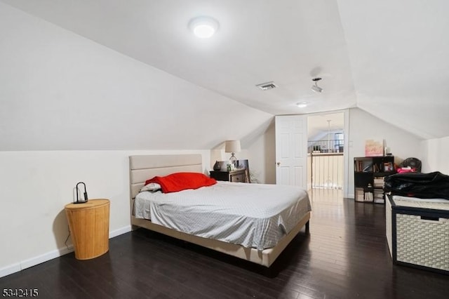 bedroom with visible vents, baseboards, lofted ceiling, and wood-type flooring