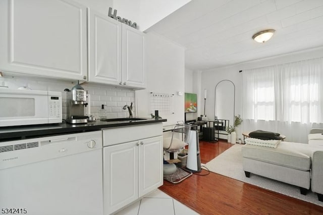 kitchen with decorative backsplash, white appliances, white cabinets, and a sink