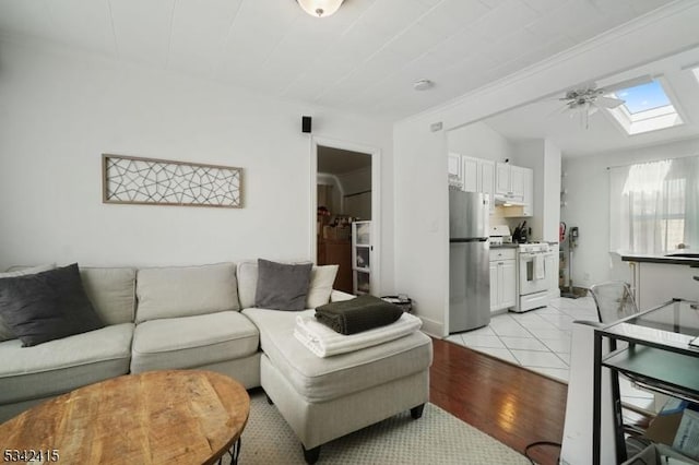 living area featuring lofted ceiling with skylight and light wood-type flooring