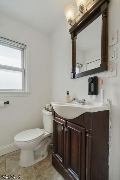 half bathroom with vanity, toilet, and baseboards