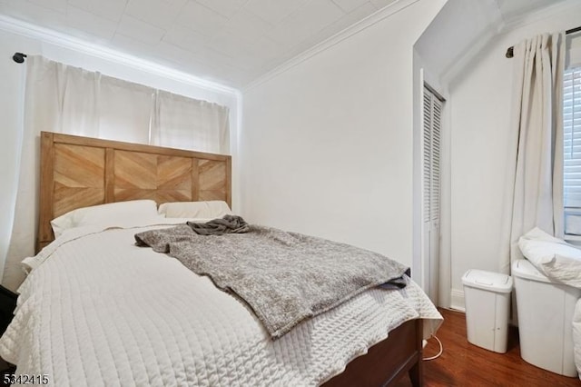 bedroom featuring a closet, crown molding, and wood finished floors