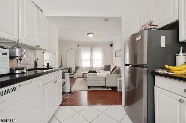 kitchen featuring white appliances, light tile patterned floors, dark countertops, and open floor plan