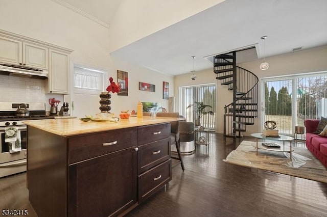 kitchen featuring tasteful backsplash, stainless steel range with gas cooktop, light countertops, cream cabinetry, and dark wood-style flooring