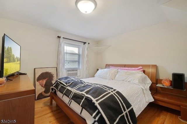 bedroom with cooling unit and wood finished floors