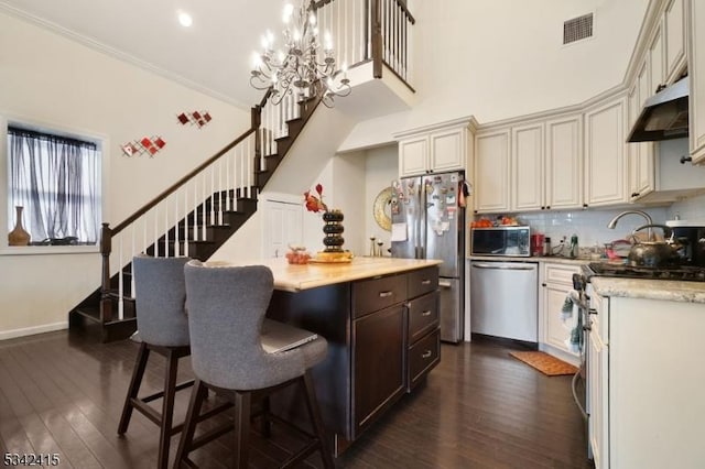 kitchen with visible vents, a center island, under cabinet range hood, stainless steel appliances, and dark wood-style flooring