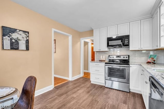 kitchen with black microwave, light wood finished floors, electric stove, dishwasher, and tasteful backsplash