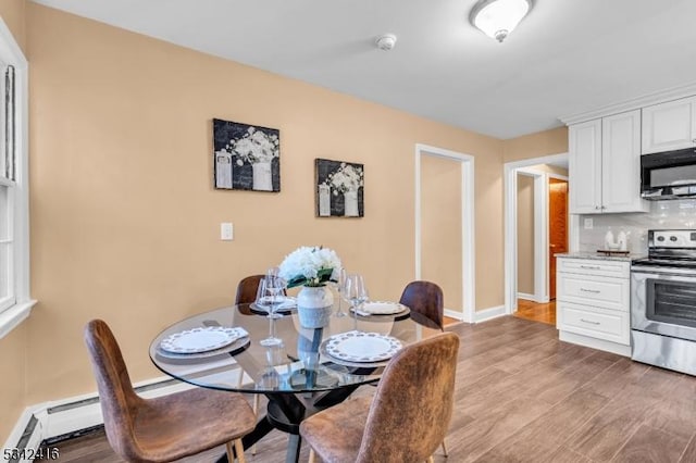 dining room with light wood-style floors, baseboards, and a baseboard heating unit