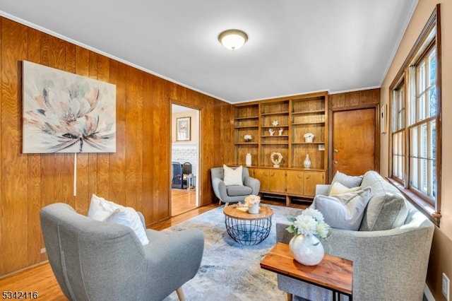 living area with crown molding, wood walls, and wood finished floors