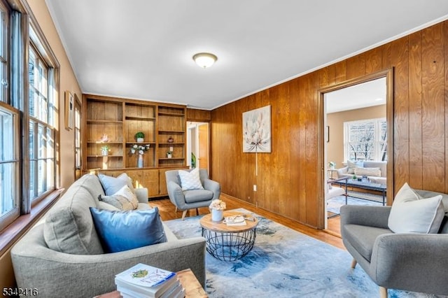 living room featuring wooden walls, ornamental molding, and wood finished floors