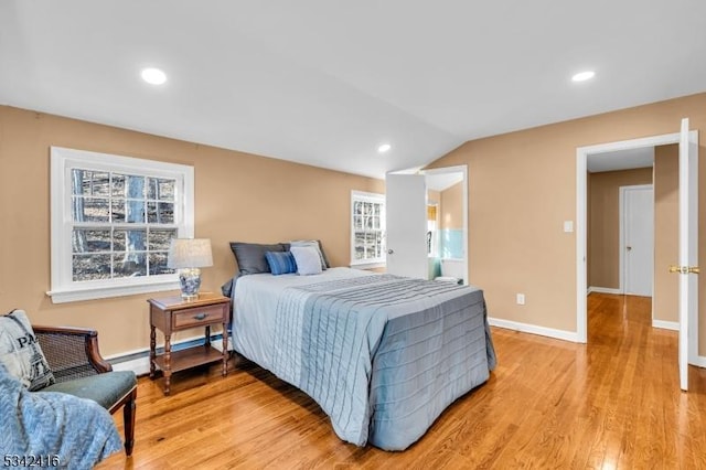 bedroom featuring vaulted ceiling, a baseboard radiator, baseboards, and light wood-style floors