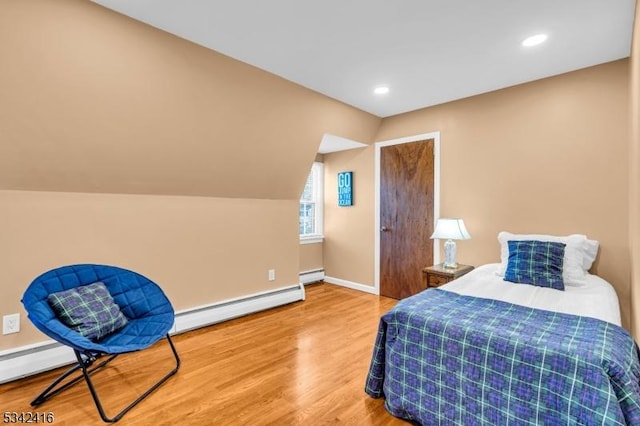 bedroom featuring lofted ceiling, baseboard heating, a baseboard heating unit, wood finished floors, and baseboards