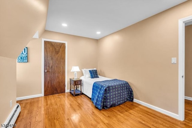 bedroom with baseboards, baseboard heating, and wood finished floors