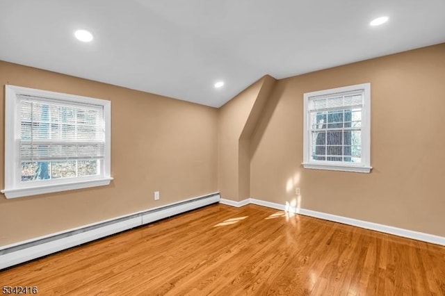 bonus room featuring a baseboard heating unit, a healthy amount of sunlight, light wood finished floors, and baseboards