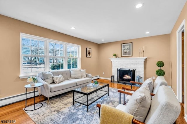 living room with a baseboard heating unit, a brick fireplace, wood finished floors, and recessed lighting