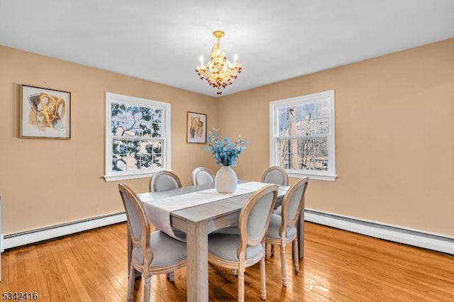 dining area with light wood-style floors, a chandelier, and baseboard heating