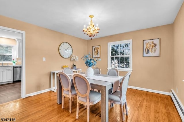 dining area featuring a baseboard heating unit, light wood-type flooring, baseboards, and a notable chandelier