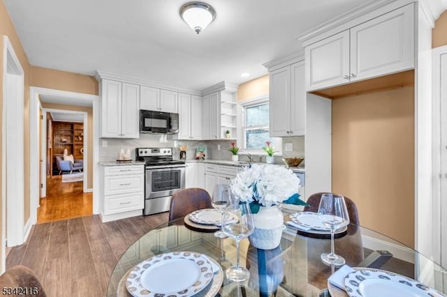 kitchen with black microwave, electric range, wood finished floors, white cabinetry, and open shelves