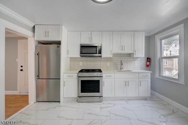 kitchen with marble finish floor, appliances with stainless steel finishes, and crown molding