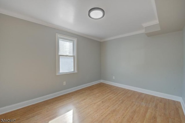 empty room featuring light wood-style flooring, baseboards, and ornamental molding