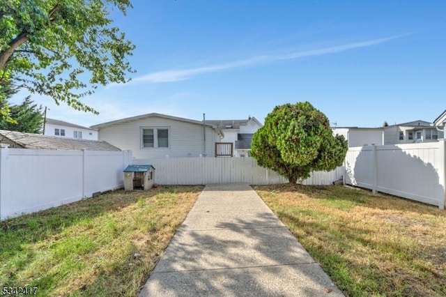 rear view of house featuring a lawn and fence private yard