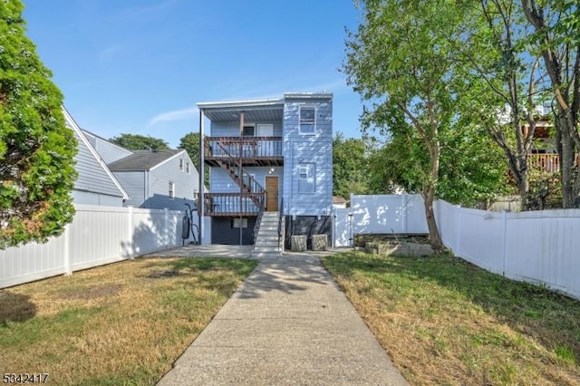 view of front of house featuring a fenced backyard, stairway, and a front lawn